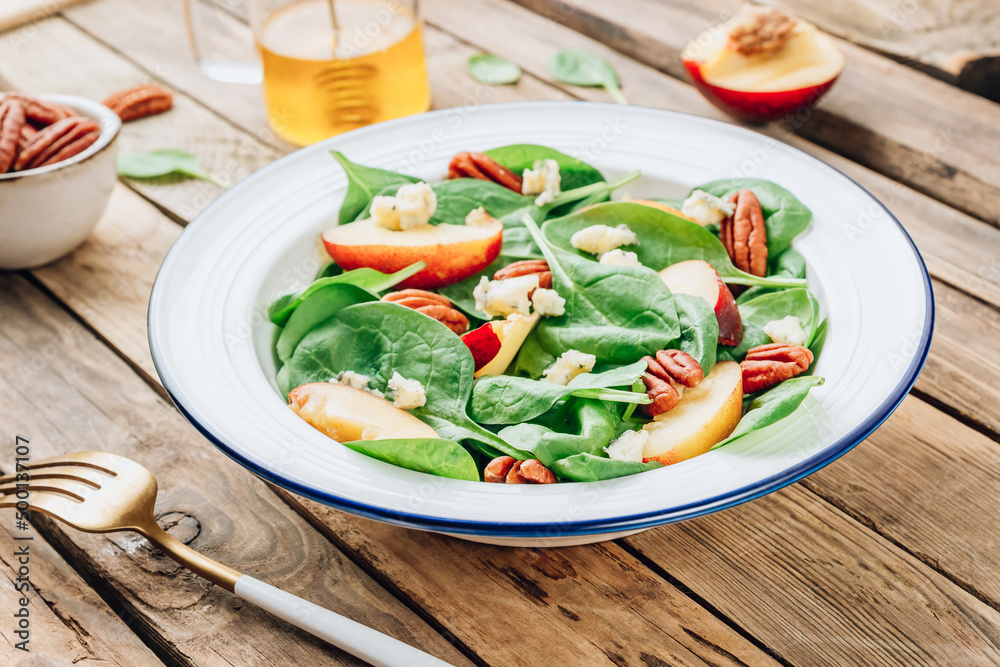 Healthy summer salad with spinach, peach, pecan nuts, blue cheese on wooden table Healthy summer salad with spinach, peach, pecan nuts, blue cheese on wooden table
