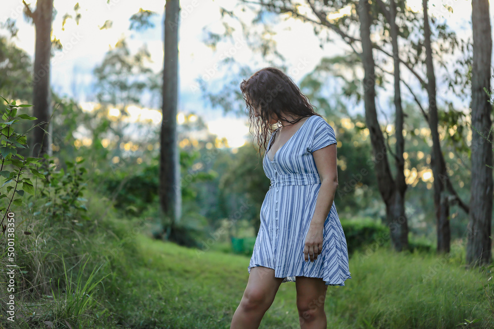 Woman in the woods wearing summer dress, face hidden by long brown hair Woman in the woods wearing summer dress, face hidden by long brown hair