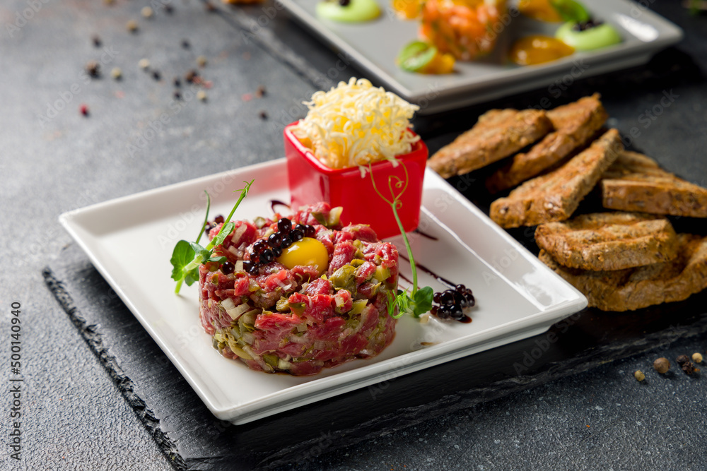 Tartare from beef on white plate with egg and croutons Tartare from beef on white plate with egg and croutons