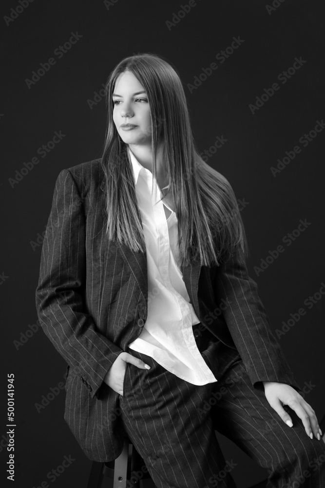 Studio portrait of fashionable girl in white button down shirt and striped oversized suit.