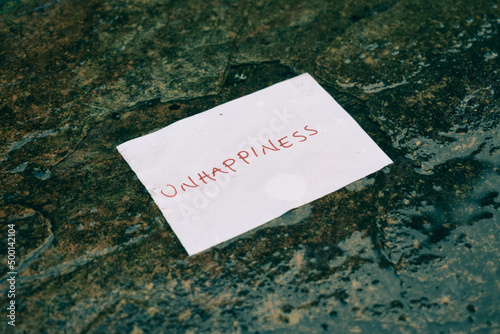 Φωτογραφία paper with text unhappiness thrown in a puddle