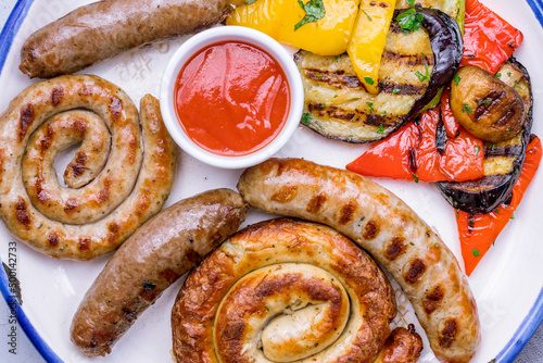 assorted sausages with sauces and grilled vegetables top view macro close up