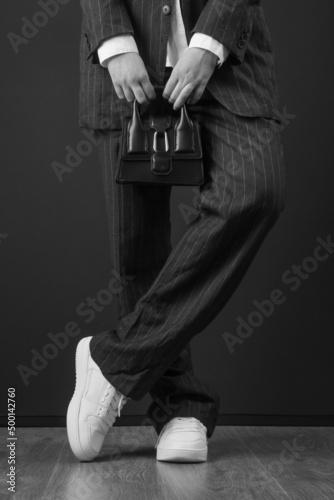 Fashionable trendy woman holding top handle mini black bag. Studio shot on black background.