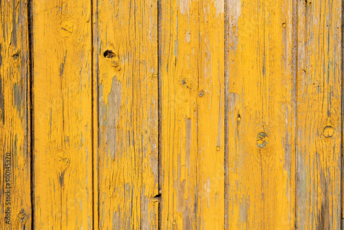 Yellow wodden planks covered with old flaking paint and visible wood patches, aged wodden door surface making a good background material