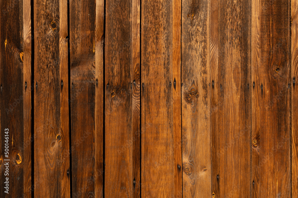 Wodden brown planks in various shades of colours, aged wodden wall of the cottage house surface making a good background material Wodden brown planks in various shades of colours, aged wodden wall of the cottage house surface making a good background material