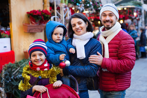 Cheerful parents with kids choosing X-mas decorations in market