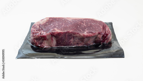 A raw piece of beef for steak in vacuum packaging isolated on white background. High-quality photo.