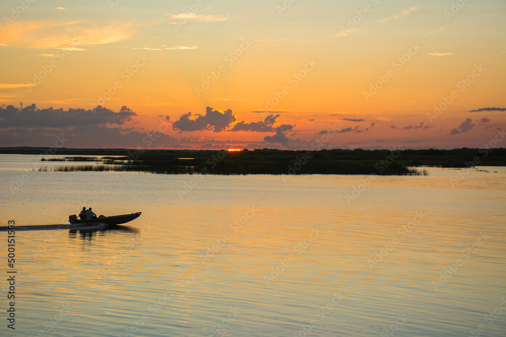 Boat speeding across the water at sunset on a lake along the St Johns River in central Florida
