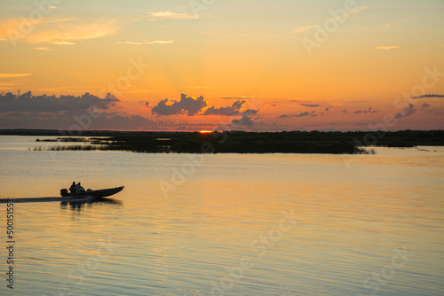 Boat speeding across the water at sunset on a lake along the St Johns River in central Florida © Ryan Tishken