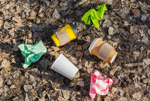 Coffee paper cups, crumpled sheets of paper are lying around in the forest. Pollution of the environment with household waste. View from above photo