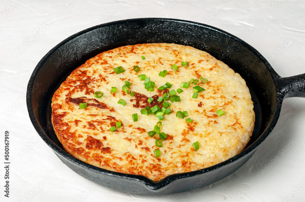 Swiss traditional dish - potato pancakes in a frying pan, decorated with green onions close-up. Swiss traditional dish - potato pancakes in a frying pan, decorated with green onions close-up.
