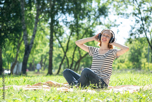 Young woman happens to have music in a summer park © adam121