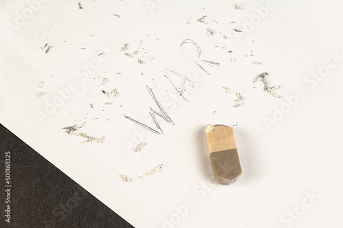 Fototapeta Naklejka Na Ścianę i Meble -  Half-erased with an eraser is the word WAR. Handwritten word on white paper.