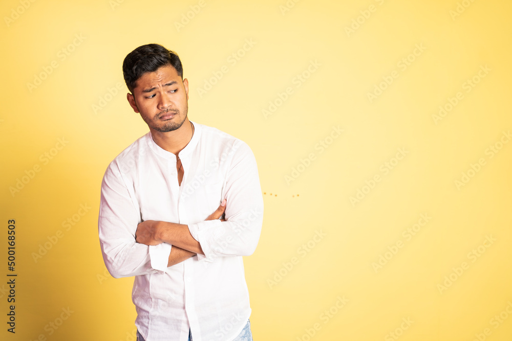 asian young man with bored expression with hands crossed on isolated background asian young man with bored expression with hands crossed on isolated background