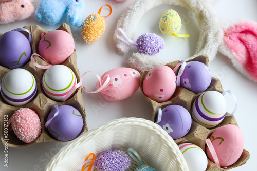 Colored Easter decorations and eggs in trays, rabbits, a basket with eggs on a white background, close-up. Holiday concept