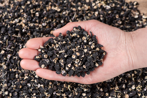 Fotografia dry black wolfberry in hand  on table
