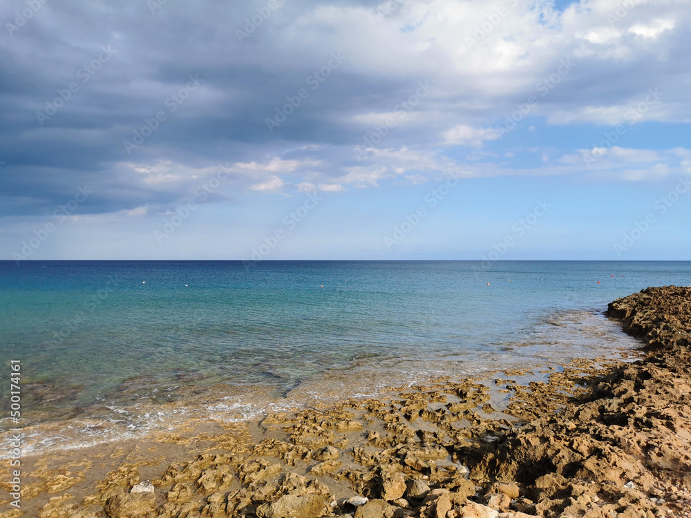 Stone coast of the Mediterranean Sea, turquoise water against a dramatic and blue sky. with clouds. and sea water.