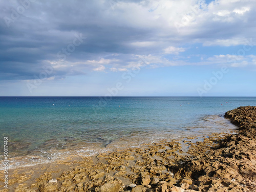 Stone coast of the Mediterranean Sea  turquoise water against a dramatic and blue sky. with clouds. and sea water.