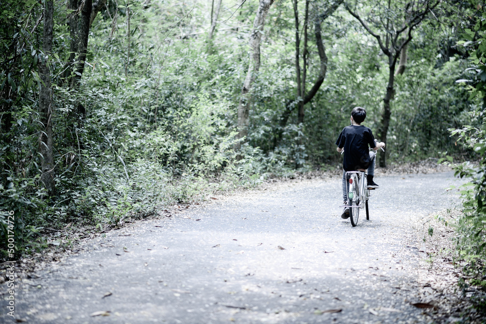 Obraz premium Teenager boy riding bicycle in the park with happy family
