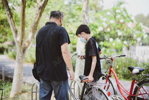 Teenager boy riding bicycle in the park with happy family