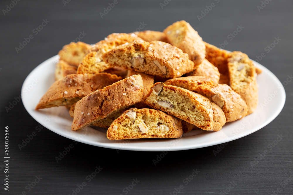 Homemade Italian Cantuccini with Almonds on a Plate on a black background, side view. Crispy Almond Cookies. Close-up. Homemade Italian Cantuccini with Almonds on a Plate on a black background, side view. Crispy Almond Cookies. Close-up.
