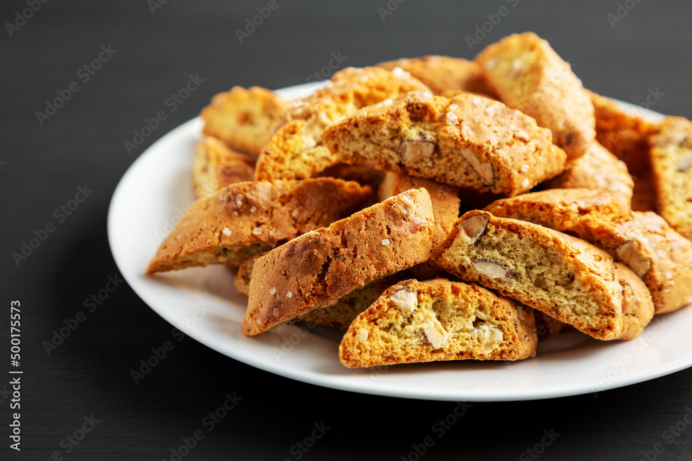 Homemade Italian Cantuccini with Almonds on a Plate on a black background, side view. Crispy Almond Cookies. Close-up.