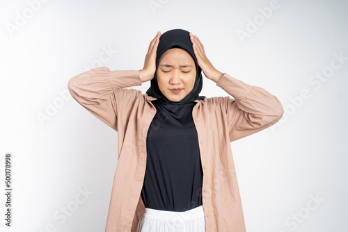 Asian woman in hijab holding head with headache on isolated background © Odua Images