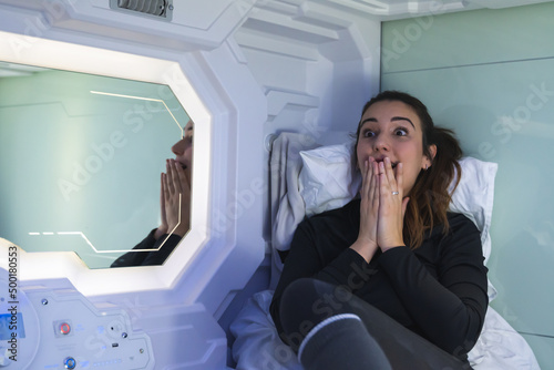 Obraz na płótnie Brunette woman very surprised and worried about the news she sees on television in the capsule bedroom. w salonie