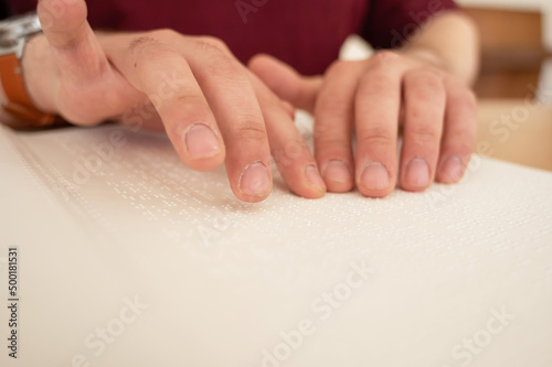 Visually impaired man reading a braille book. 