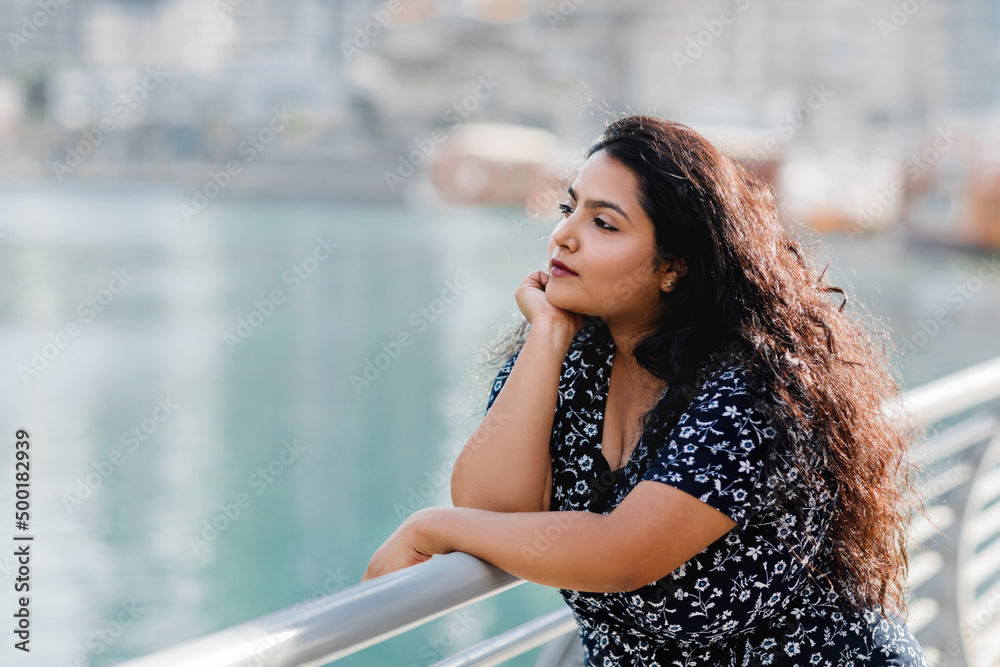 Portrait of a beautiful Indian girl standing at the parapet on the embankment.