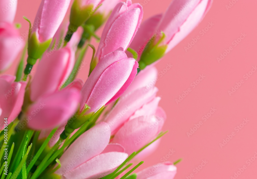 Artificial pink flowers on a pink background.