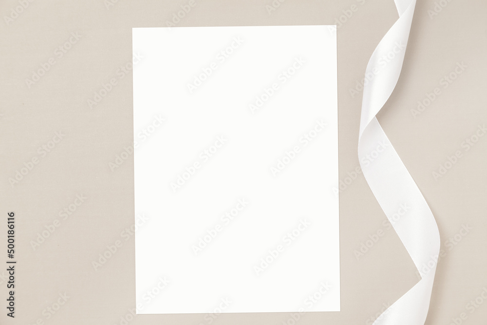 Wedding invitation or greeting card mockup with white satin ribbon on a beige background. - obrazy, fototapety, plakaty 