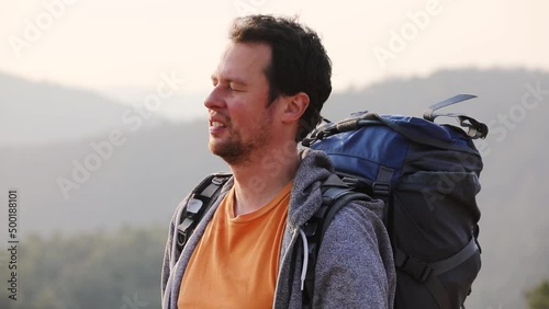 Young man drinks water during hiking on sunny day