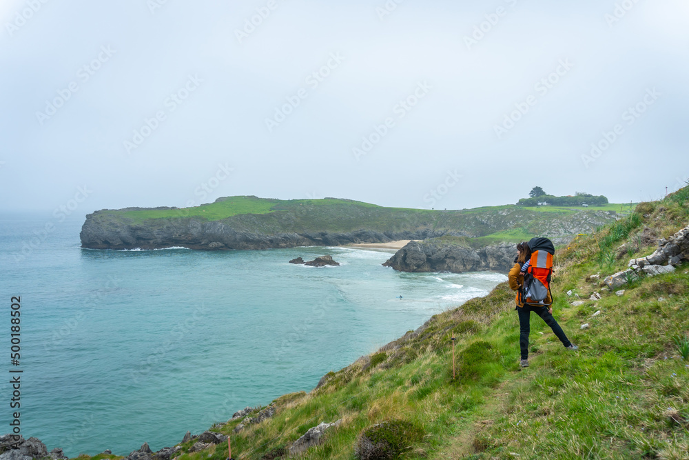 A young woman with her son walking towards Playa de Troenzo and Playa de la Tayada on the Borizu peninsula in the town of Llanes. Asturias. Spain