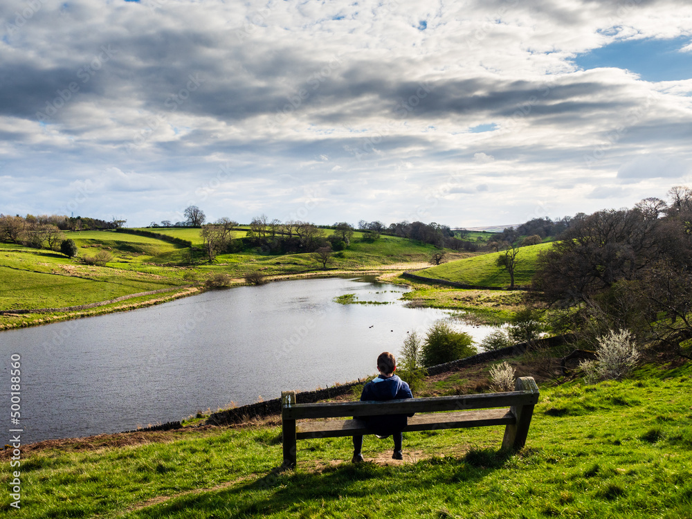 John O' Gaunt reservoir in Nidderdale in Yorkshire. A beautiful Spring afternoon and the views are lovely. A person is sat on a bench enjoying the views