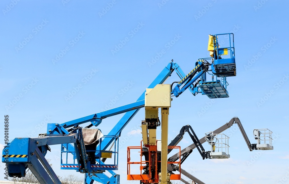 Group of aerial working platforms of cherry picker against blue sky. Back and side view. Group of aerial working platforms of cherry picker against blue sky. Back and side view.