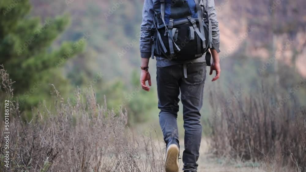 Man hikes with a big backpack walks away from a camera Man hikes with a big backpack walks away from a camera