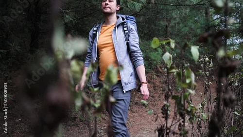 Young man hikes ina forest with a backpack
