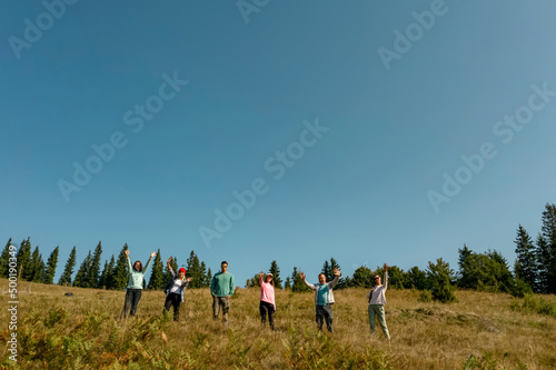 Group of happy tourists on hill in mountains  low angle view