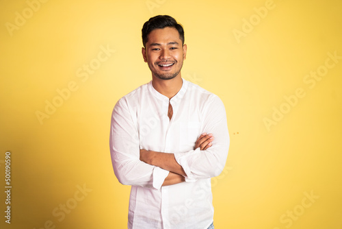 asian young man wearing white shirt smiling with arms crossed on isolated background