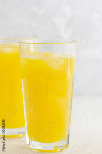 Orange lemonade in glasses on a light table.
