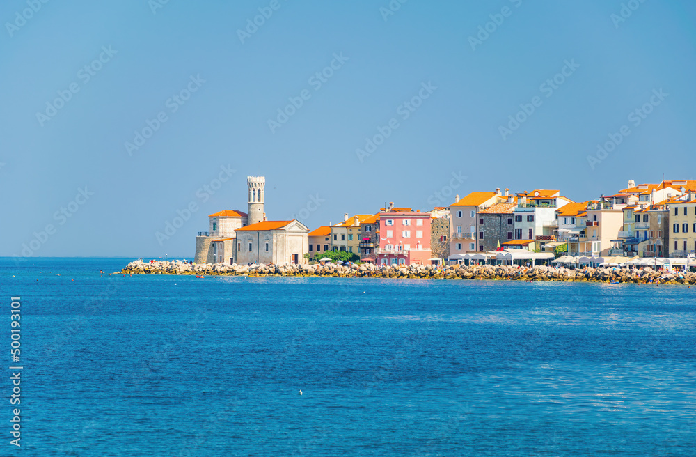 Picturesque view of coastline of Adriatic sea with colorful houses and lighthouse at sunny summer day, Piran, Slovenia