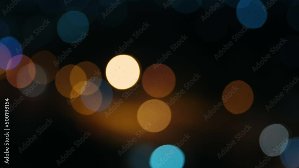 Beautiful glittering bokeh in dark blurry background at night. The round colorful bokeh shine from car lights in traffic on city street. It reflect lonely capital city lifestyle. Abstract concept. Beautiful glittering bokeh in dark blurry background at night. The round colorful bokeh shine from car lights in traffic on city street. It reflect lonely capital city lifestyle. Abstract concept.