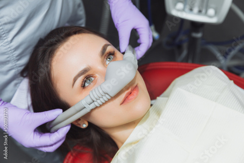 dentist puts inhalation sedative mask on his patient.