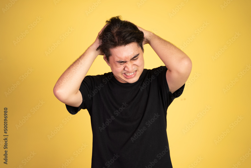 Stressed asian young young man holding head on isolated background Stressed asian young young man holding head on isolated background