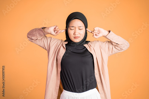 Woman in hijab cover her ear on isolated background © Odua Images
