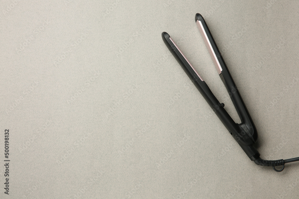 Modern flat hair iron on grey background, top view. Space for text Modern flat hair iron on grey background, top view. Space for text