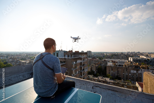 Fotografie, Tablou Young technician man flying UAV drone with remote control in city