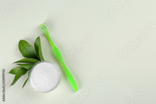 Toothbrush and bowl of baking soda on beige background, flat lay. Space for text