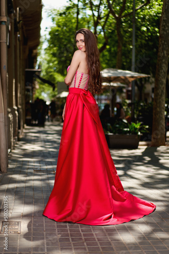 Attractive beautiful girl in a red dress standing on the city